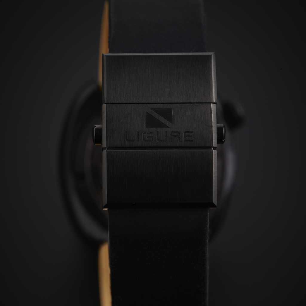 Close-up of a black DLC clasp with 'LIGURE' branding on a dark background